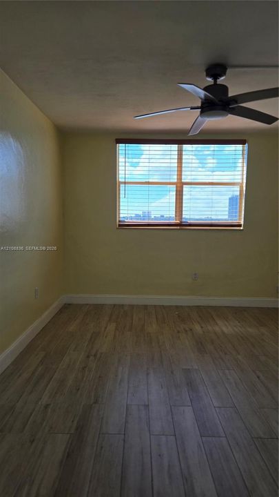 Wood-finish flooring, multi-pane window with blinds, and ceiling fan with integrated light fixture
