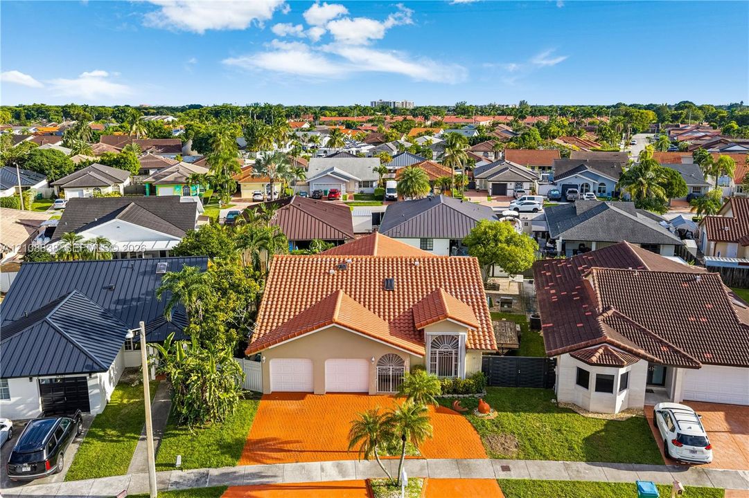 Aerial perspective featuring a terracotta-tiled roof, double-car garage, arched window detail, and paved driveway