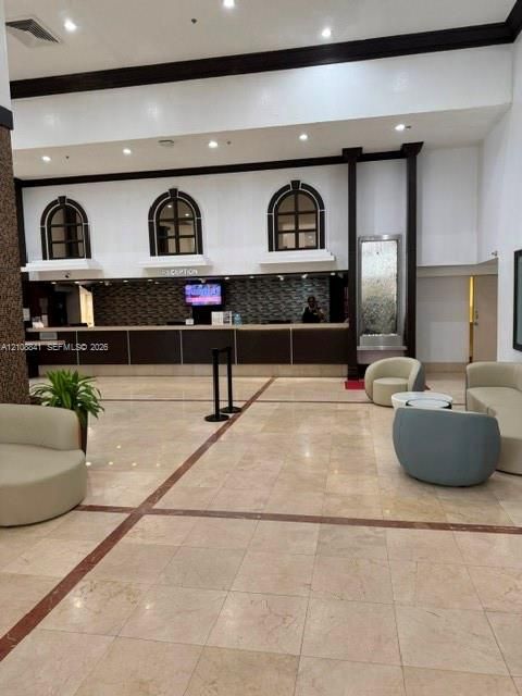 Lobby featuring stone tile flooring, an elongated service counter with a mosaic tile backsplash, built-in recessed arch windows, and an integrated wall-mounted water feature