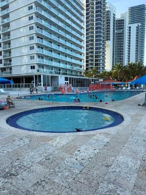 Outdoor swimming pool and circular spa featuring tile finishes and natural stone decking