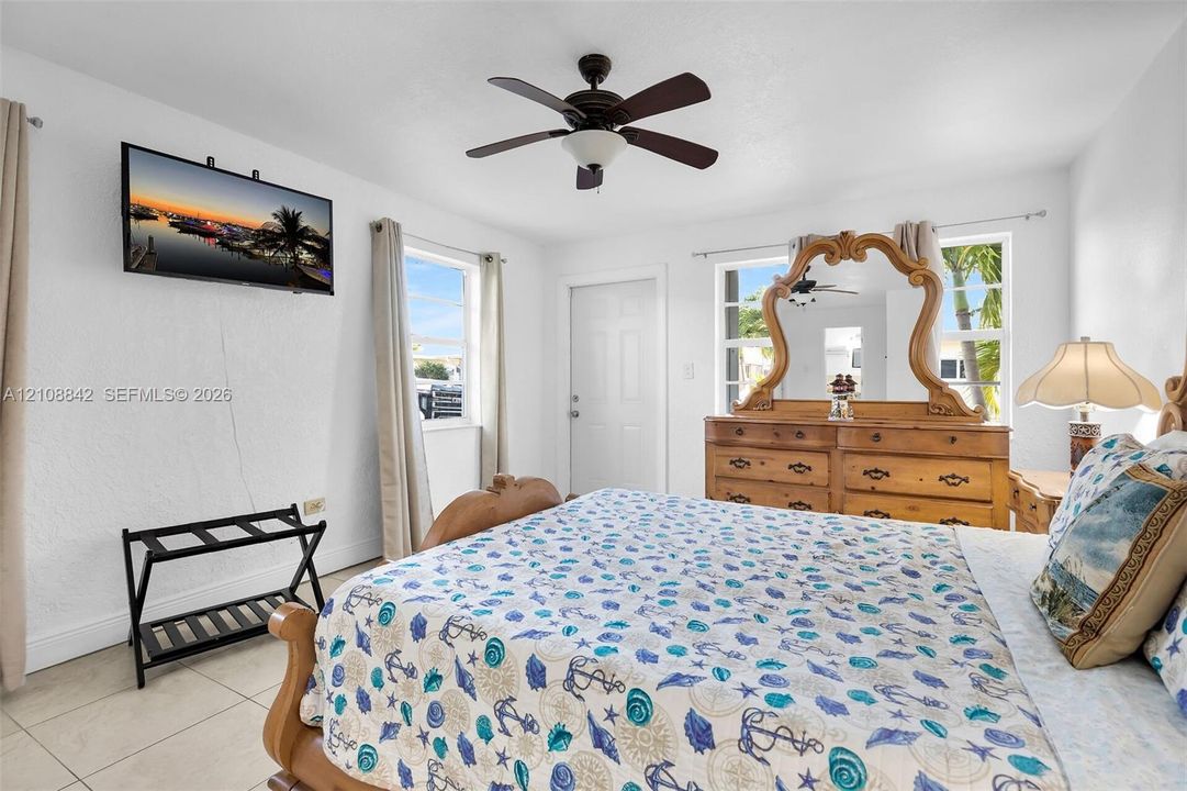 Room featuring neutral tile flooring, multi-pane windows with natural light, and a ceiling-mounted fan with light fixture