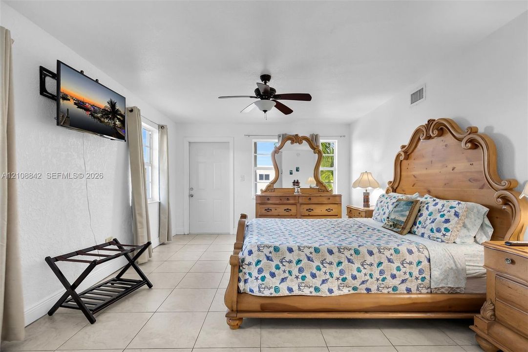 Light-filled room featuring neutral tile flooring, a multi-blade ceiling fan, and multi-pane windows