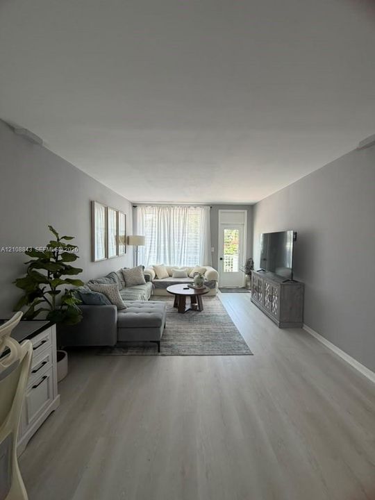 Neutral grey wall finishes, wood-finish flooring, and a glass-paneled exterior door