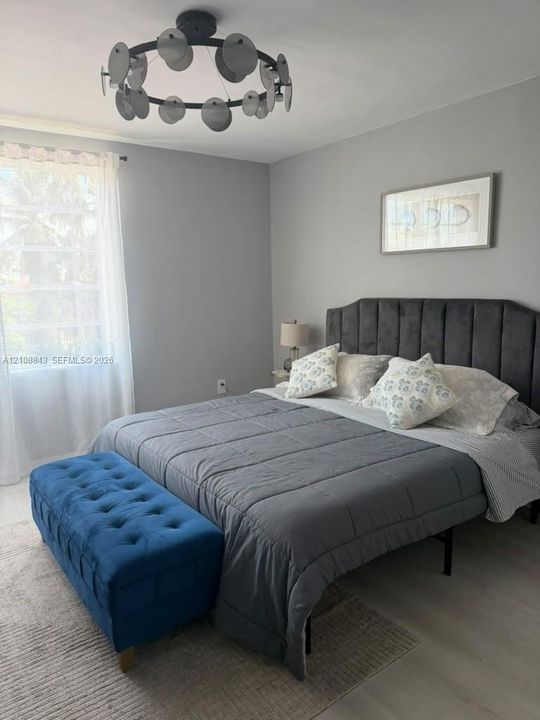 Neutral-toned interior featuring wood-finish flooring and a contemporary circular flush-mount chandelier with disc accents