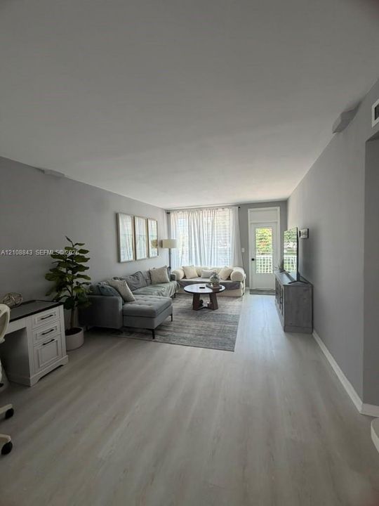 Open-concept interior featuring neutral wall tones, light wood-finish flooring, and a glass-paneled exterior door