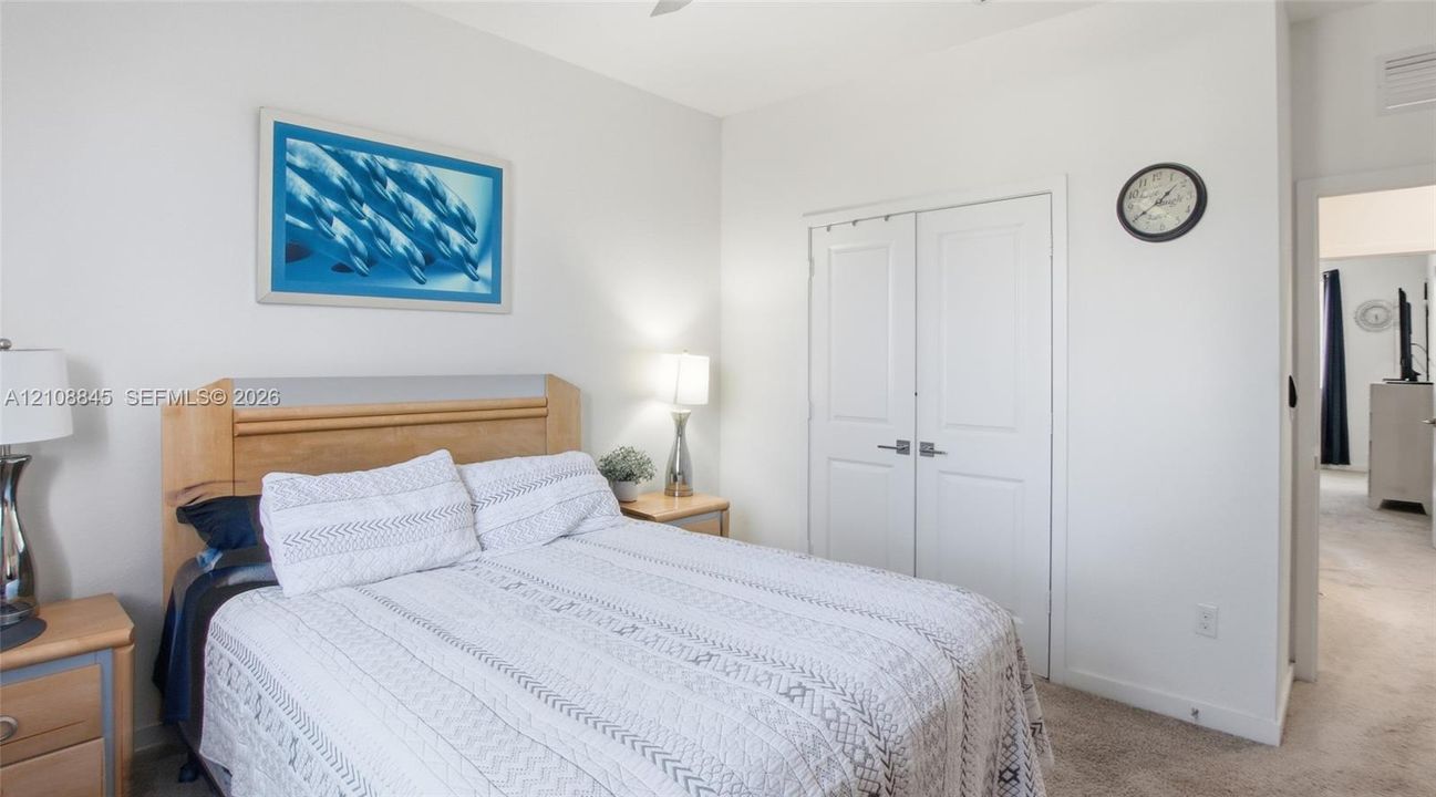 Neutral-toned interior featuring carpeting, dual-panel closet doors with satin-finish hardware, and a ceiling fan