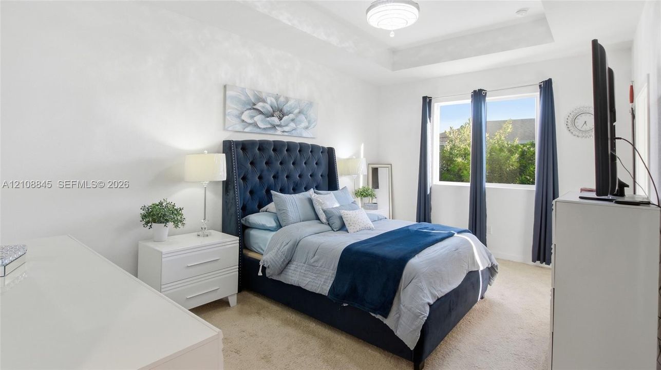 Tray ceiling, neutral wall tones, plush wall-to-wall carpeting, and a flush-mount light fixture