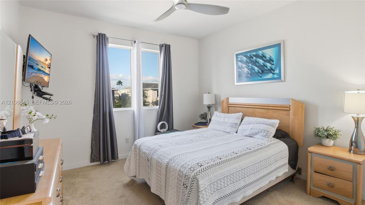 Neutral interior room featuring plush carpeting, dual-pane windows, and a ceiling-mounted fan with integrated lighting