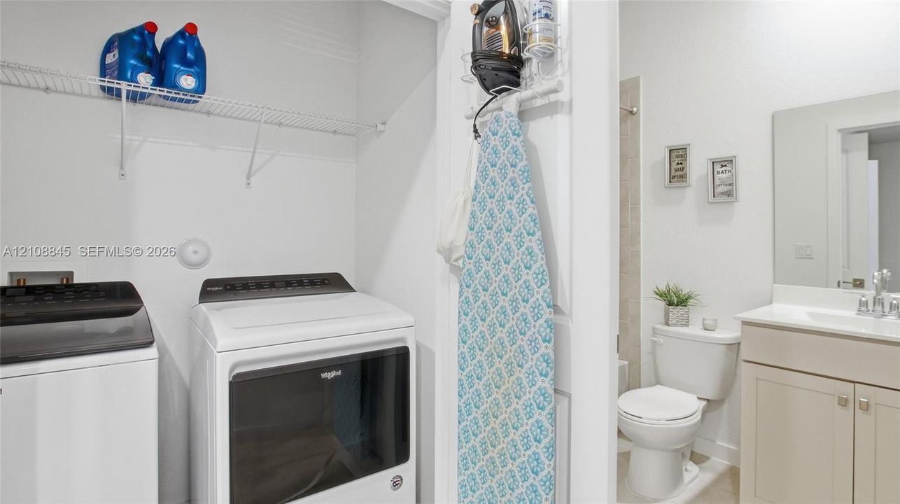 Laundry area featuring wire shelving, paired with a bathroom containing a vanity, rectangular sink, and toilet