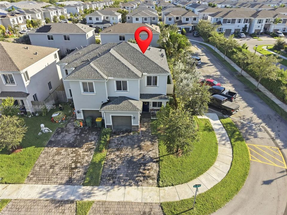 Two-story residence featuring a gray stucco exterior, multi-gabled roofline, paver driveway, and an attached two-car garage