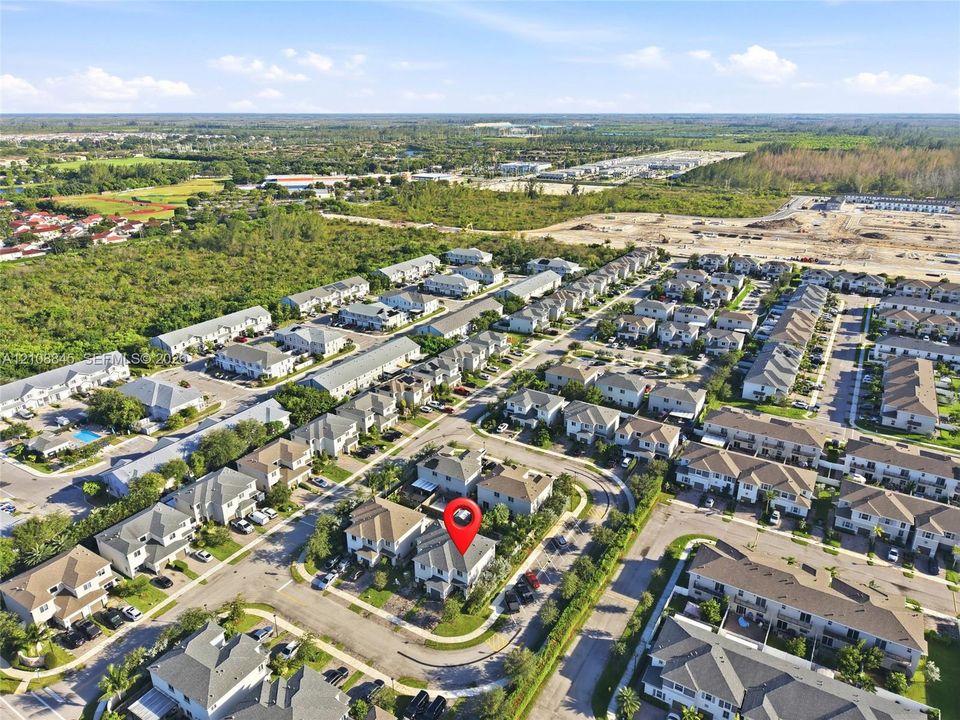 Aerial view of a residential community featuring multi-level dwellings with neutral-toned roofing, paved roadways, and integrated green spaces
