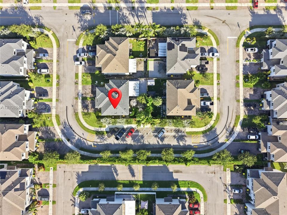 Aerial perspective of a residential property featuring a pitched roofline, fenced rear grounds, mature landscaping, and dedicated parking