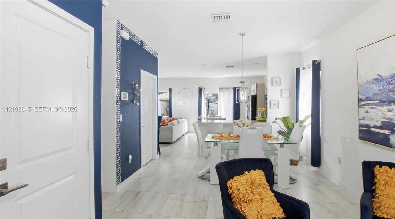 Open-concept interior featuring large-format tile flooring, bold navy blue accent walls, decorative geometric trim, and a hanging pendant light fixture