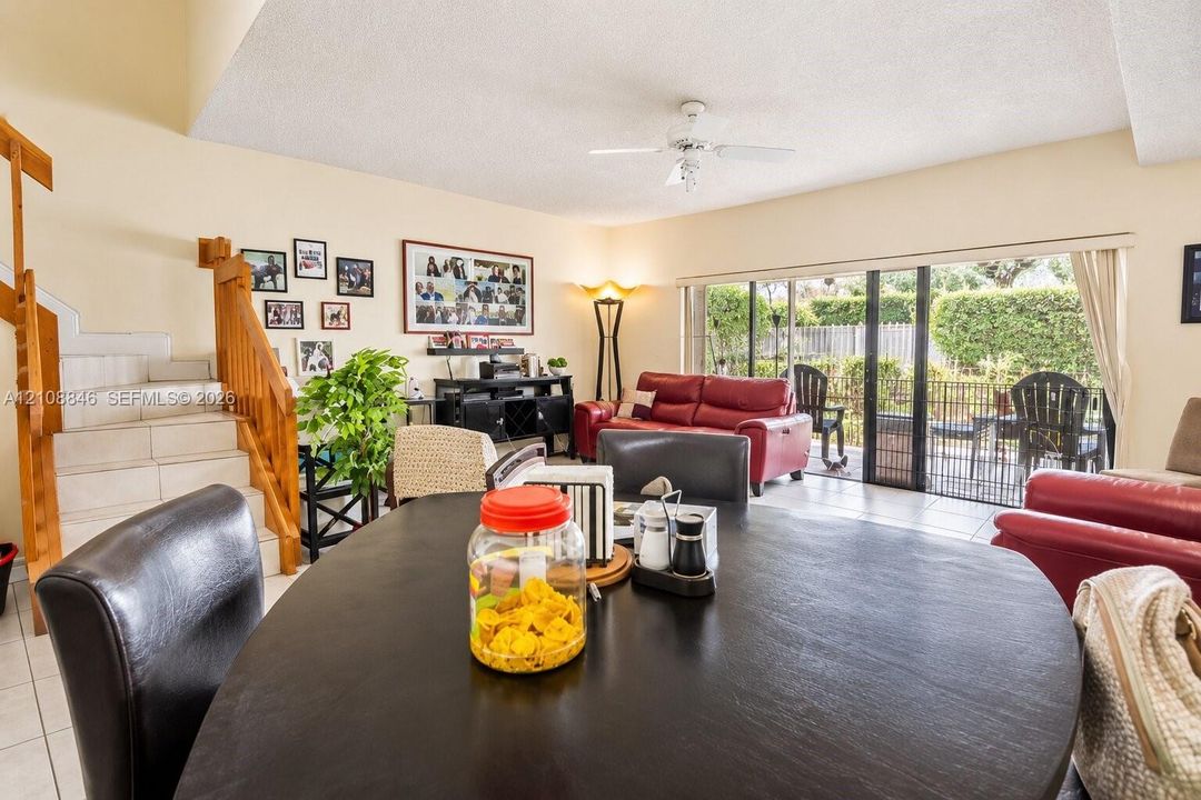 Open-concept interior featuring light-toned tile flooring, a wooden staircase with integrated railing, and expansive glass sliding doors