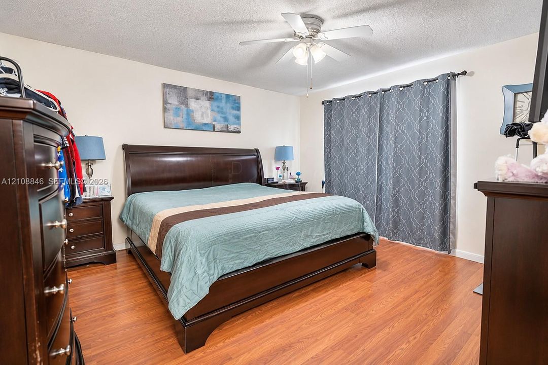 Bedroom featuring wood-finish flooring and a central ceiling fan with integrated lighting