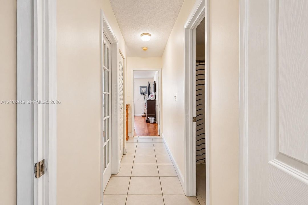 Hallway featuring ceramic tile flooring, a multi-pane glass door, louvered closet doors, and a flush-mount ceiling light fixture
