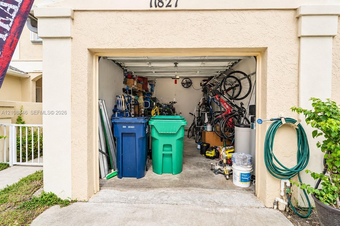 Single-car garage featuring a concrete floor, ceiling-mounted hardware, and exterior spigot