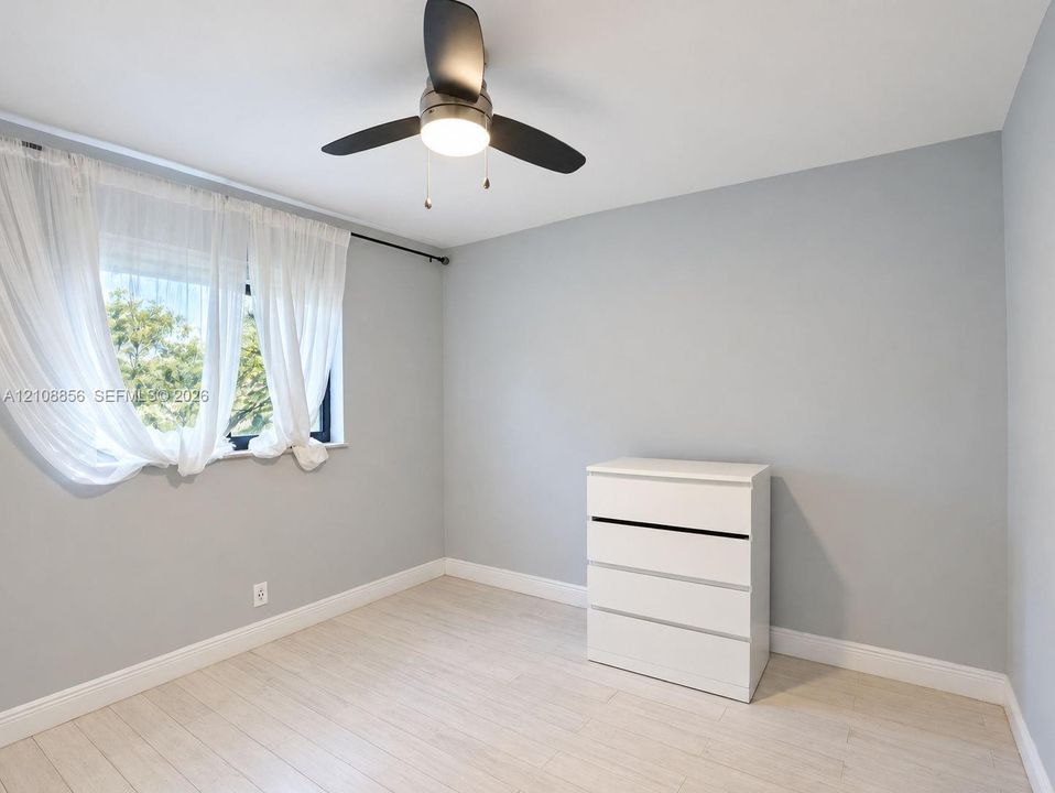 Neutral-toned walls, wood-finish flooring, and a modern ceiling fan with integrated lighting