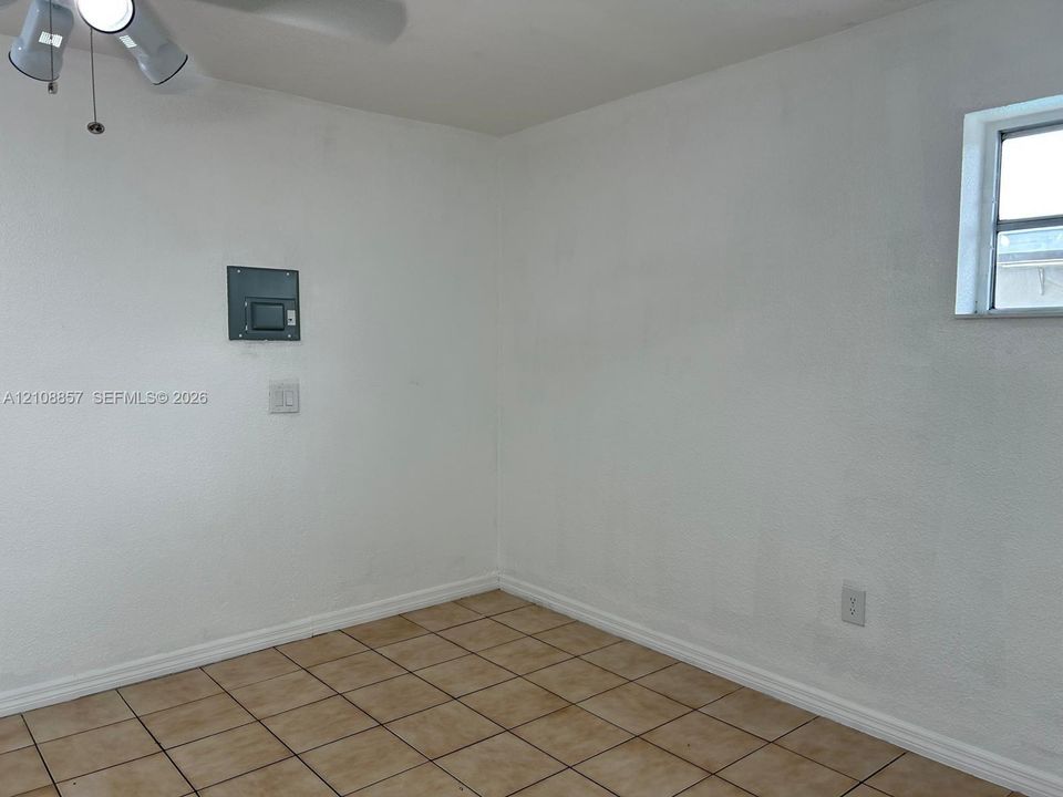 Room featuring tile flooring, a multi-light ceiling fixture, and a single-pane window
