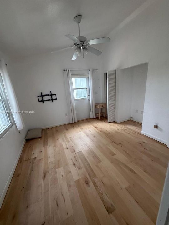 Vaulted ceilings, wood-finish flooring, ceiling fan with integrated lighting, and louvered closet doors