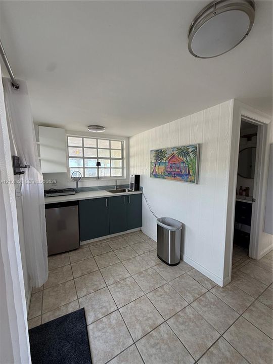 Kitchenette featuring flat-panel cabinetry, a light-toned countertop, integrated sink, and tile flooring