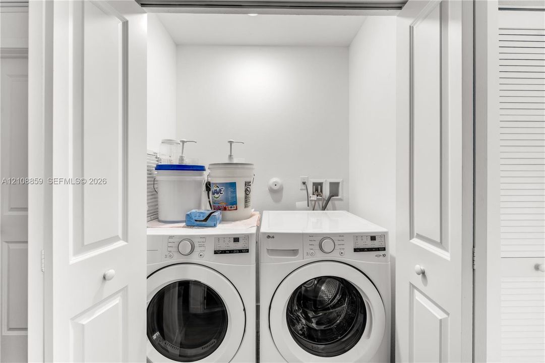 Laundry closet featuring louvered bi-fold doors, white interior finishes, and dedicated utility hookups