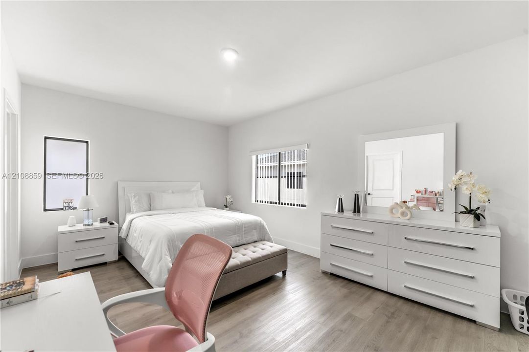 Neutral interior space featuring wood-finish flooring, crisp white walls, dual windows, and recessed ceiling lighting