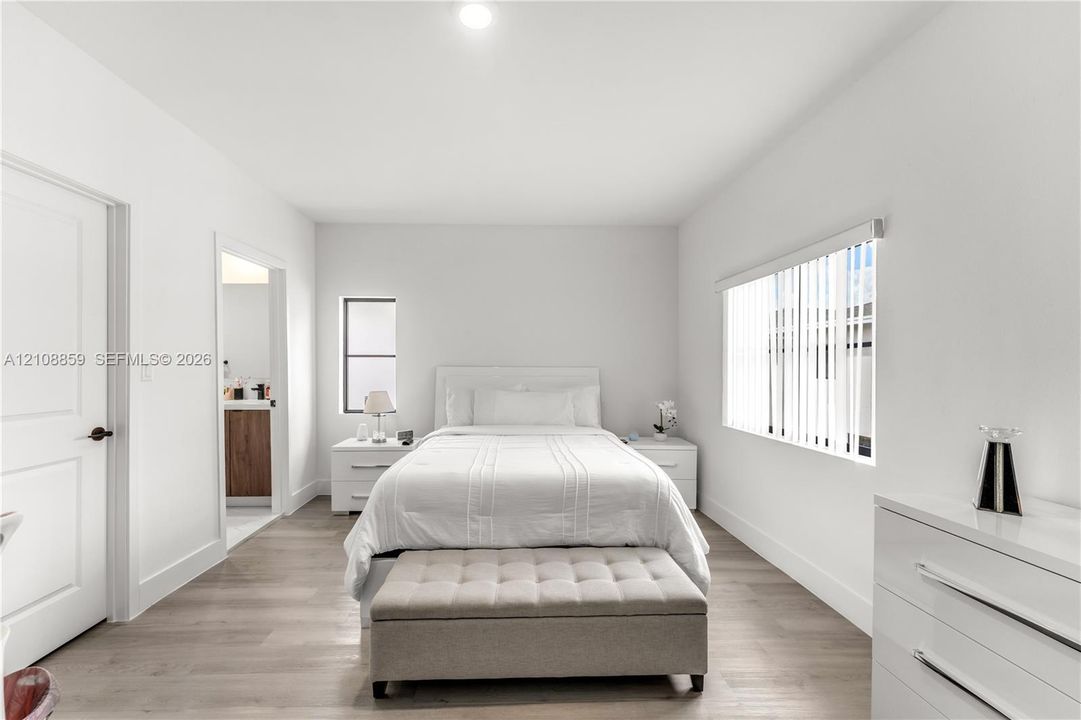 Neutral-toned wood-finish flooring, recessed ceiling lighting, and vertical window blinds