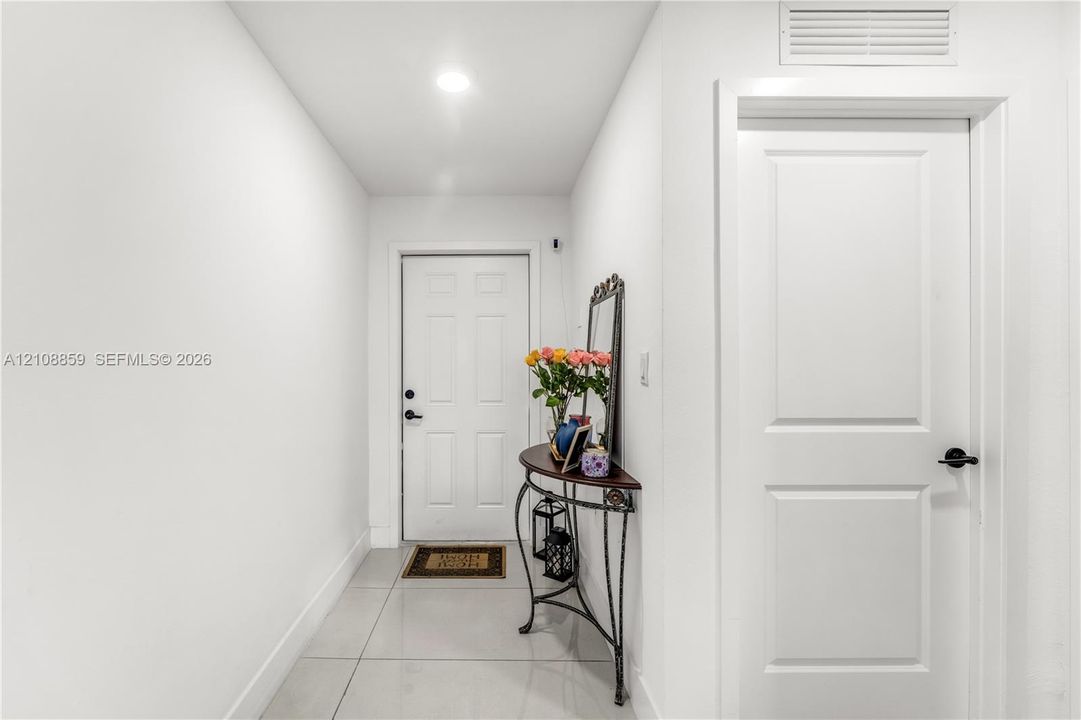 Entryway featuring large-format ceramic tile flooring, recessed lighting, and a six-panel front door with matte black hardware