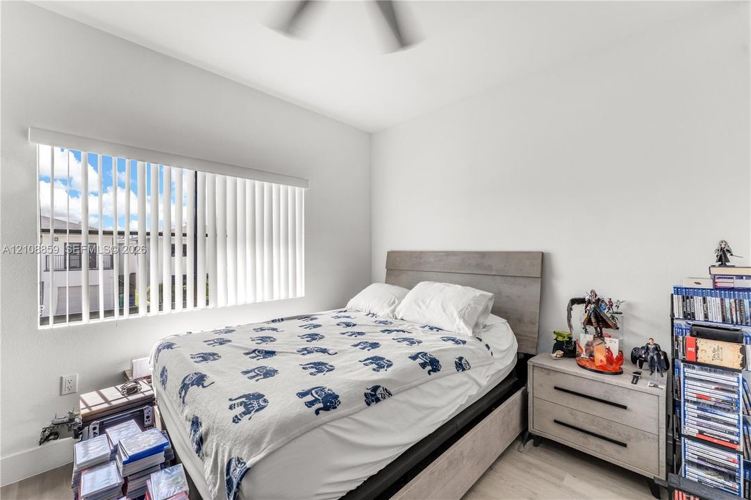 Neutral-toned room featuring a ceiling fan and vertical window blinds