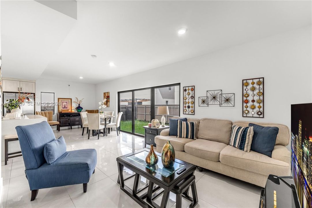 Open-concept interior featuring large-format tile flooring, recessed lighting, and expansive glass sliding doors