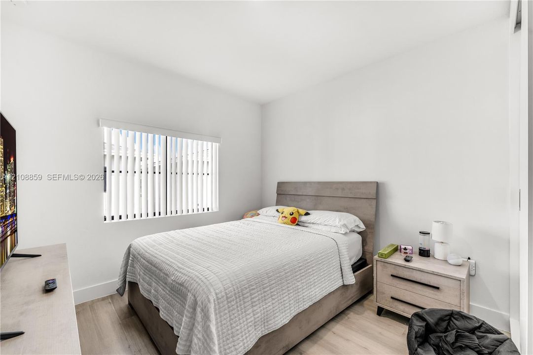Neutral-toned walls, wood-finish flooring, and white vertical window blinds