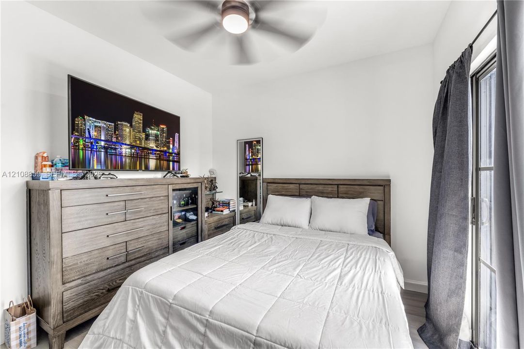 Bedroom featuring wood-finish flooring, a ceiling fan with integrated lighting, and a sliding glass door
