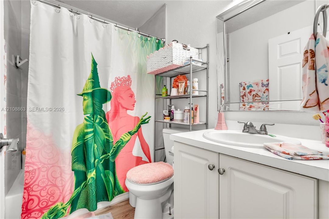 Bathroom featuring a white vanity cabinet, integrated sink with a dual-handle faucet, and a large mirror with a metallic frame