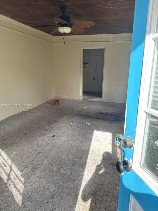 Enclosed space featuring a wood-plank ceiling, ceiling fan with light fixture, and door with multipane glass inlay