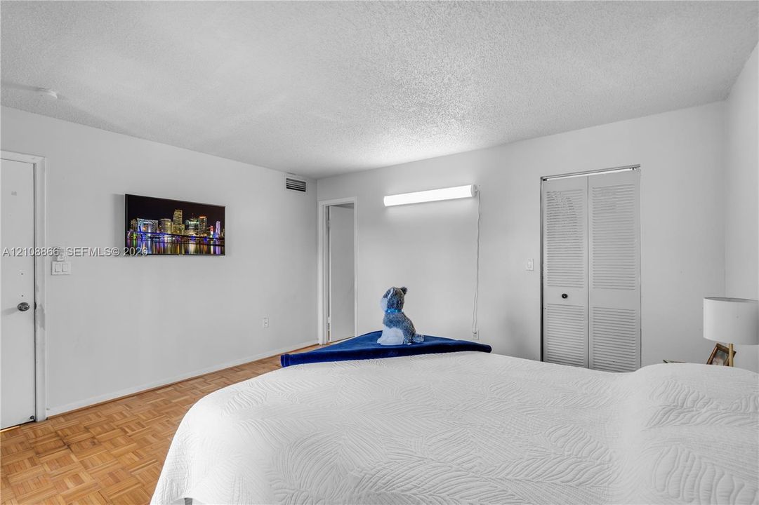 Parquet wood-finish flooring, white walls, and a closet with bifold louvered doors