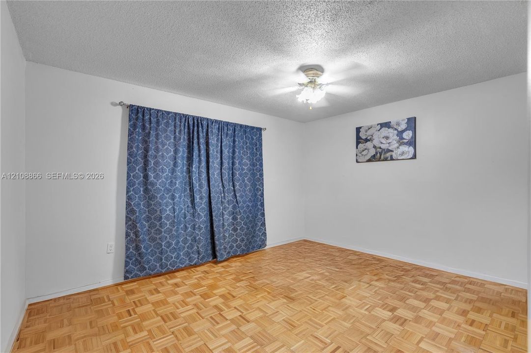 Parquet wood-finish flooring, textured ceiling, and a central ceiling fan with multi-light fixture