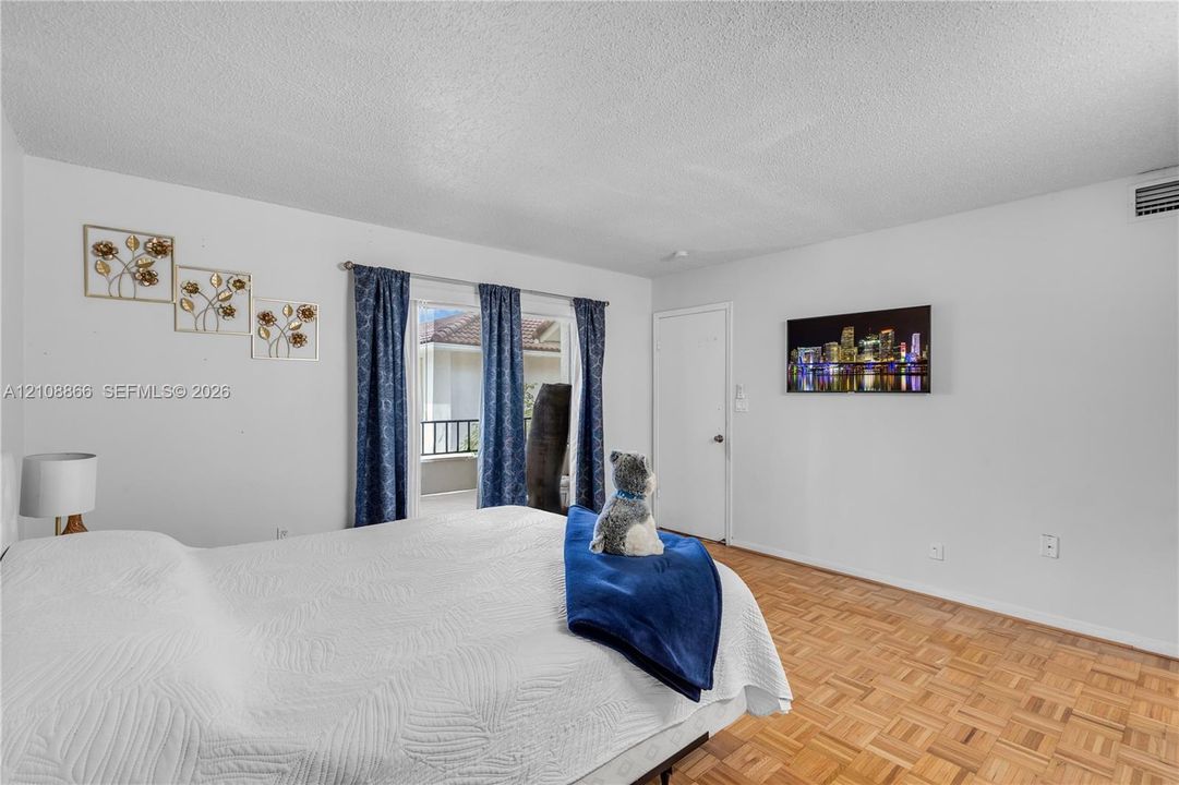 Interior space featuring wood-finish parquet flooring, textured ceiling, and a sliding glass door providing external access to a balcony with a railing