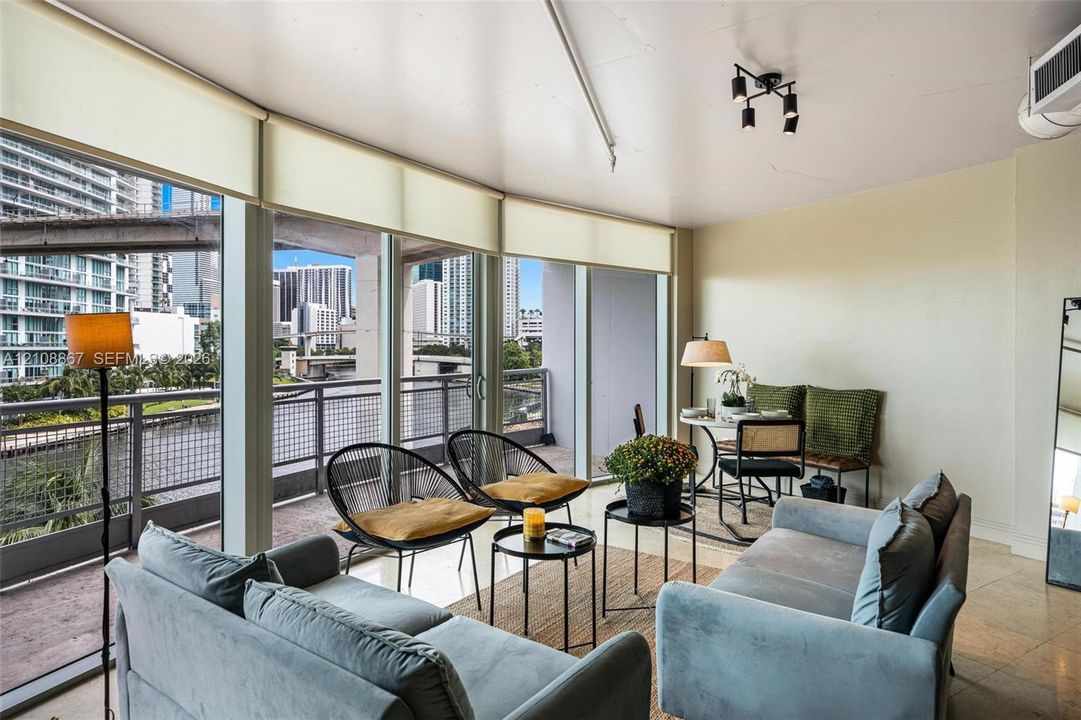 Floor-to-ceiling windows, stone-finish flooring, sliding glass door, and metal-railed balcony