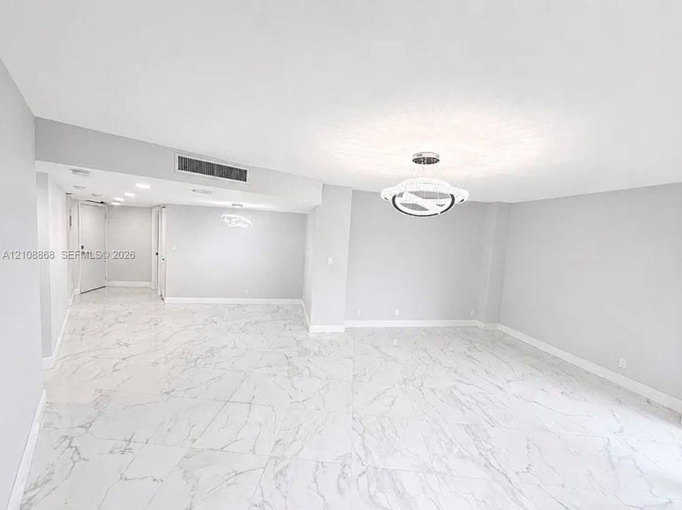 Large-format white tile flooring with grey veining, contemporary integrated circular pendant lighting, and recessed ceiling illumination