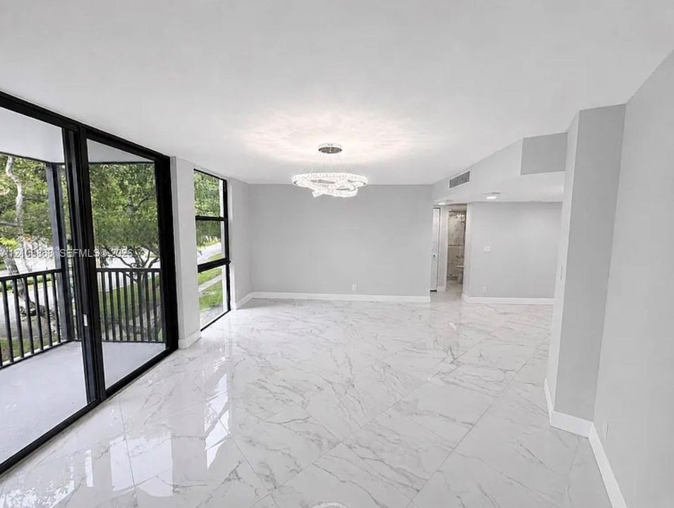 Large-format tile flooring with polished finish, expansive sliding glass doors, black-framed balcony railing, and modern multi-tiered LED chandelier