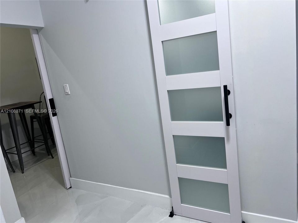 White sliding barn door featuring five frosted glass panels and matte black hardware