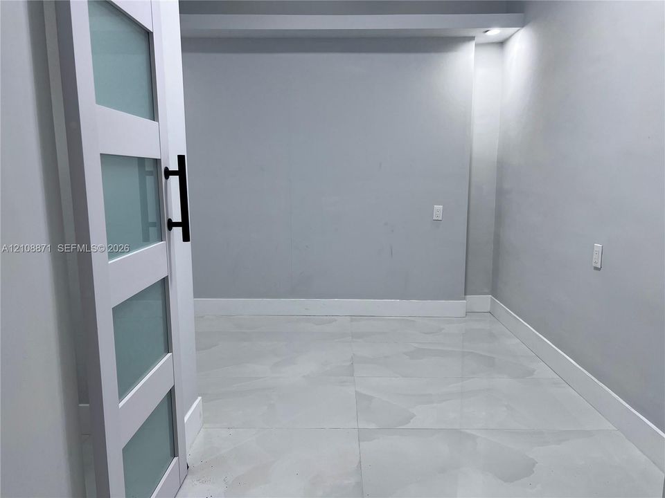 Interior space featuring a sliding door with frosted glass panels, matte black hardware, and large-format porcelain tile flooring