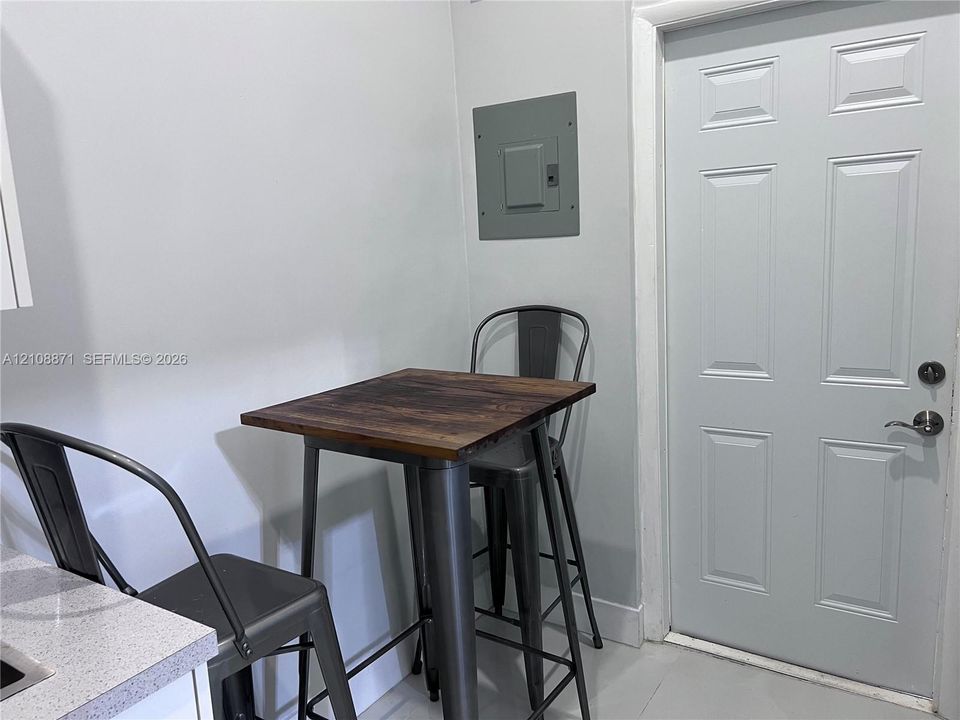 Six-panel door with brushed metal hardware, neutral-toned walls, and a recessed electrical service panel