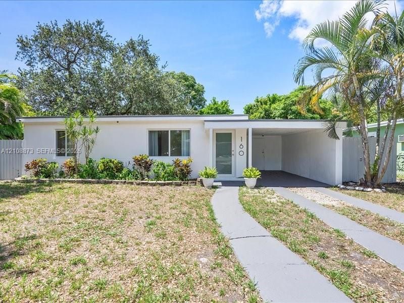Single-story residence featuring a stucco exterior, attached carport, concrete driveway, and mature landscaping