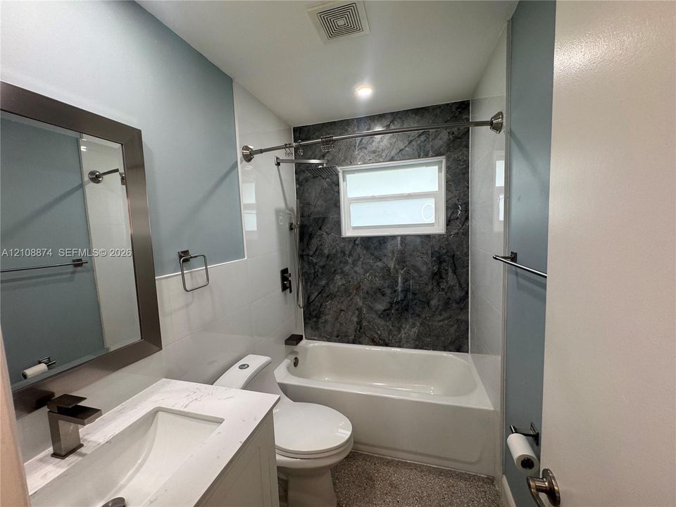 Bathroom featuring a vanity with a white composite countertop, integrated rectangular sink, and metallic faucet