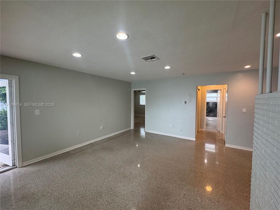 Interior space featuring polished terrazzo flooring, recessed lighting, and white-painted brick accents