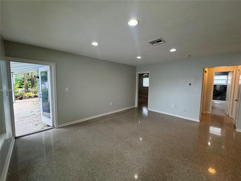 Polished terrazzo flooring, recessed lighting, and a glass-paneled door opening to an exterior concrete patio