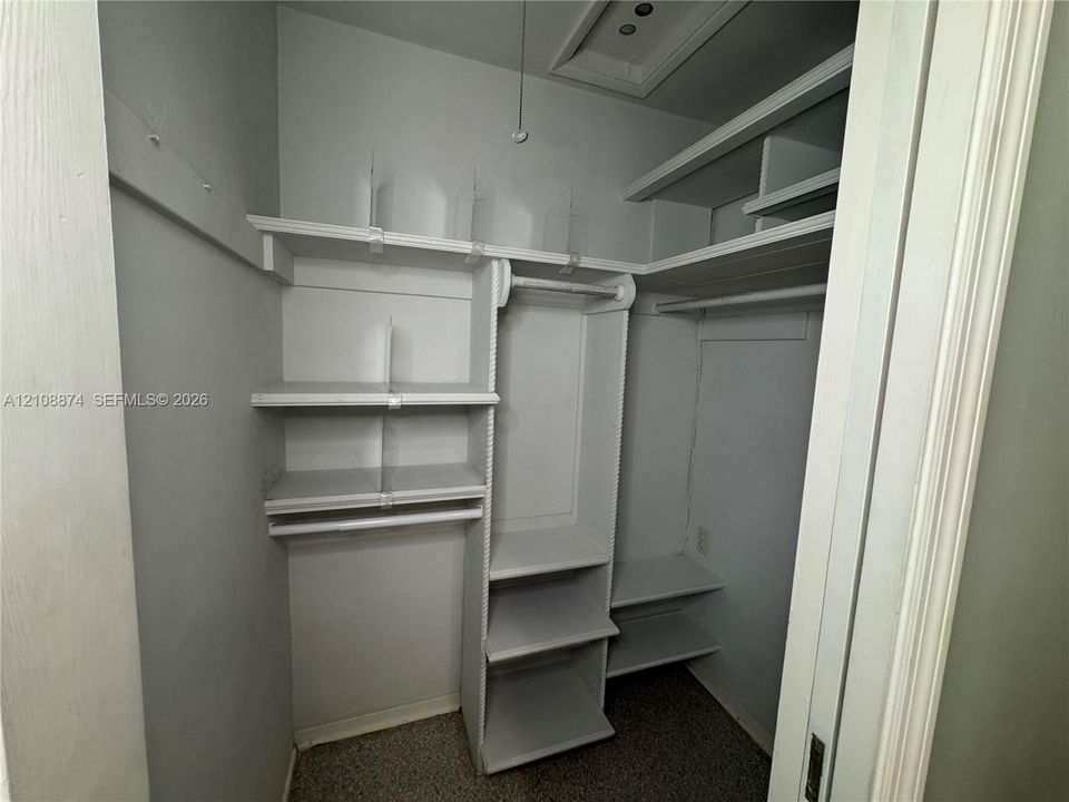 Storage closet featuring tiered built-in shelving, vertical dividers, and integrated garment rods