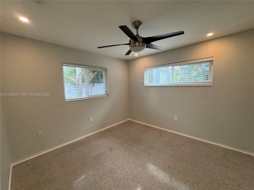 Neutral-toned walls, recessed lighting, ceiling fan with light fixture, horizontal window blinds, and speckled hard-surface flooring